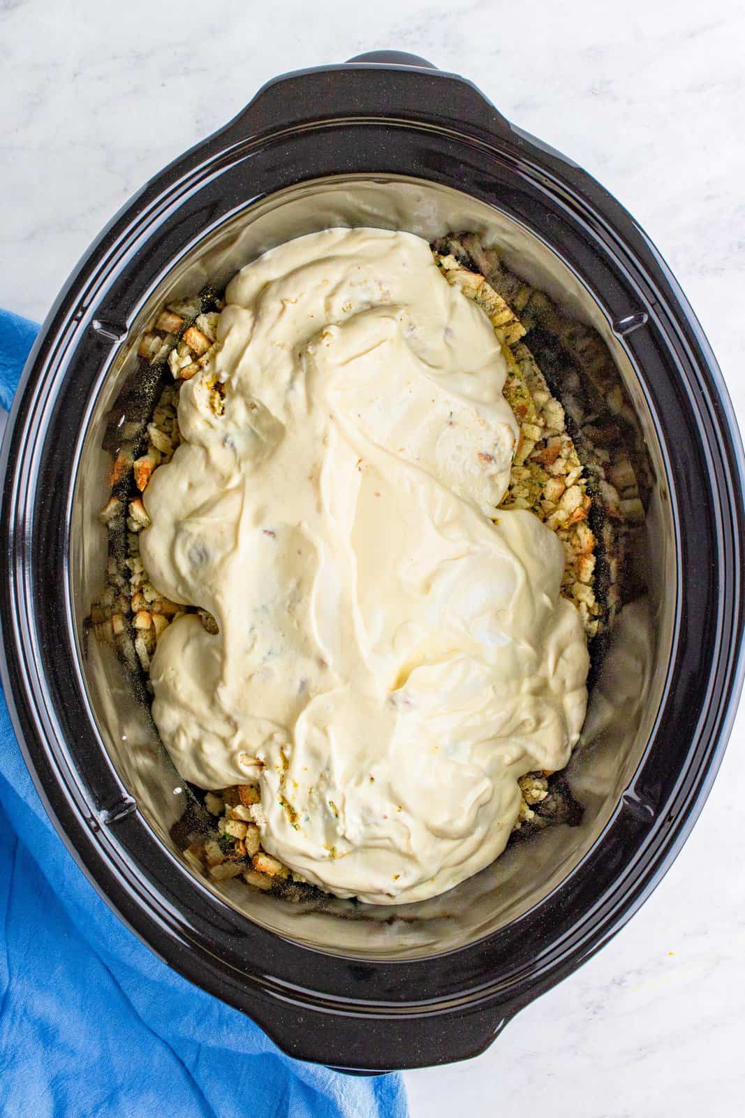 cream of chicken soup and sour cream spread on top of stuffing mixture in slow cooker.
