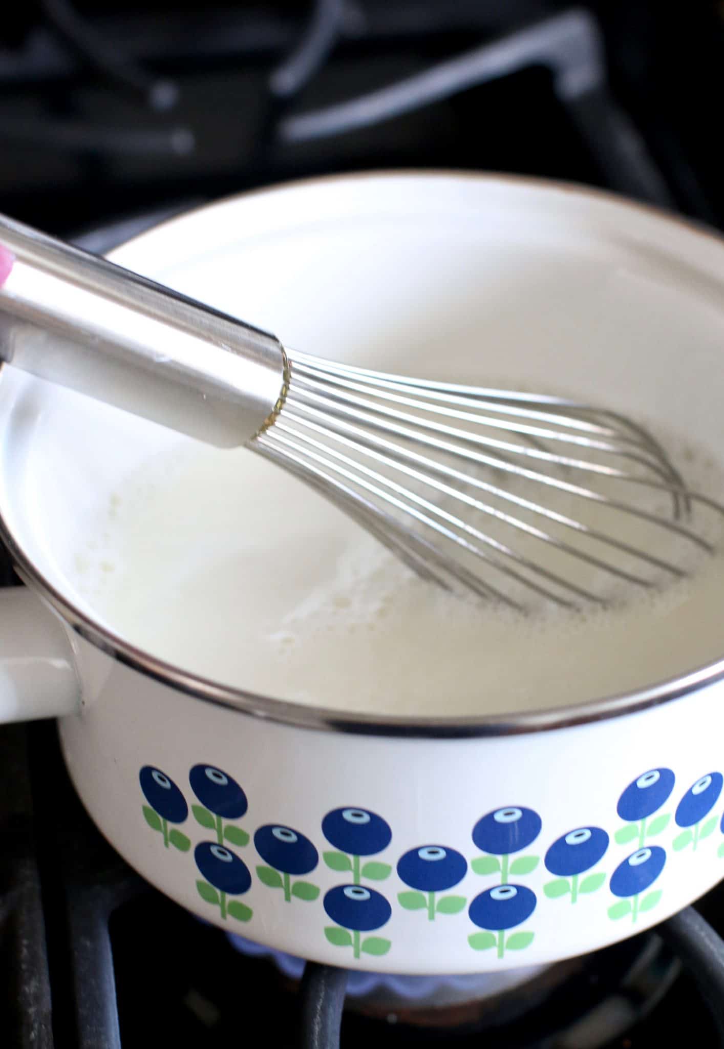 milk, sugar, cornstarch being whisk together in a white saucepan. 