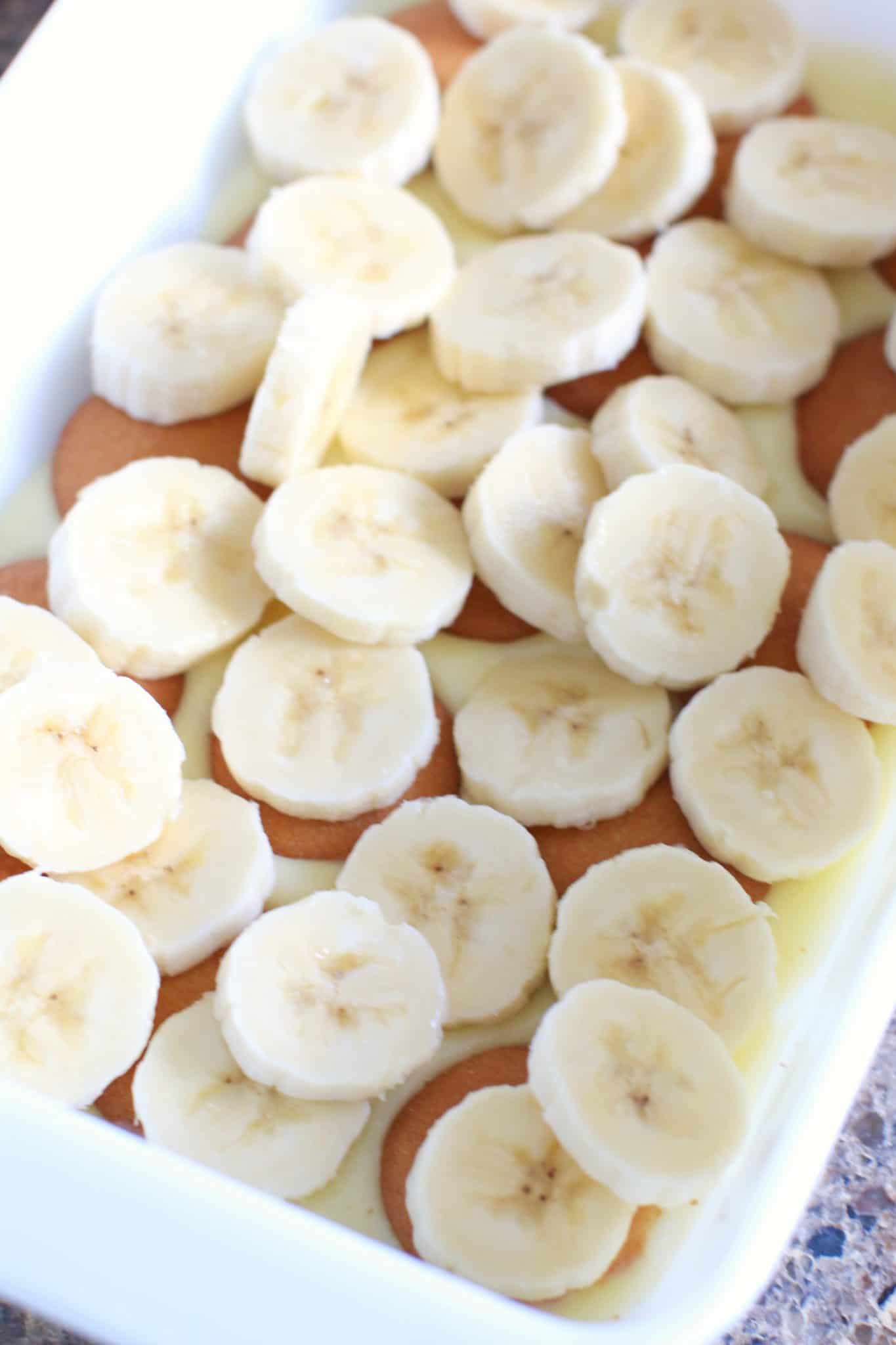 layered bananas on top of Nilla wafers in white baking dish. 