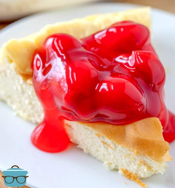 slice of cheesecake on a plate and topped with cherry pie filing. 
