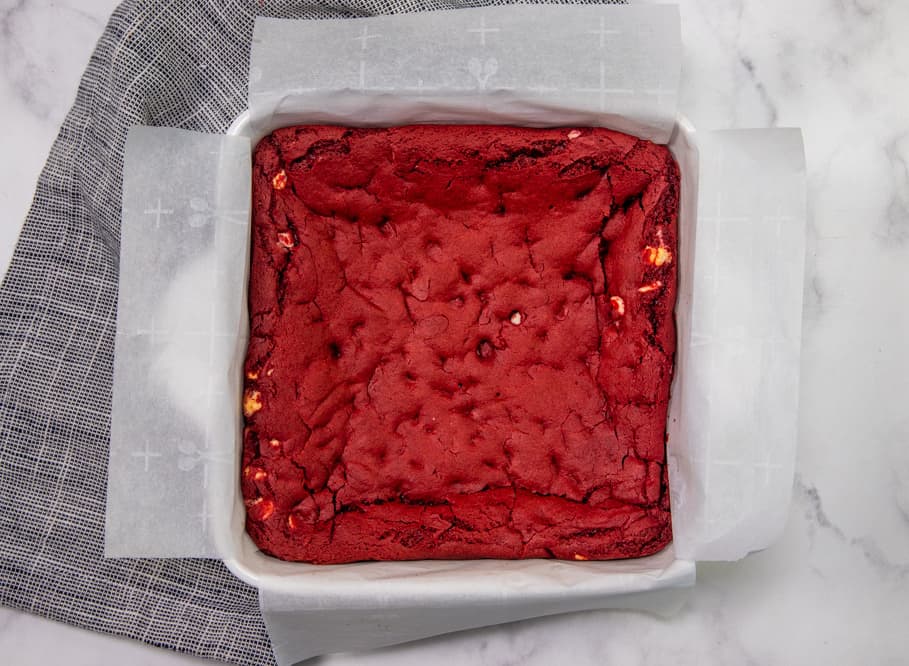 fully baked red velvet cake bars in a parchment paper line baking dish.