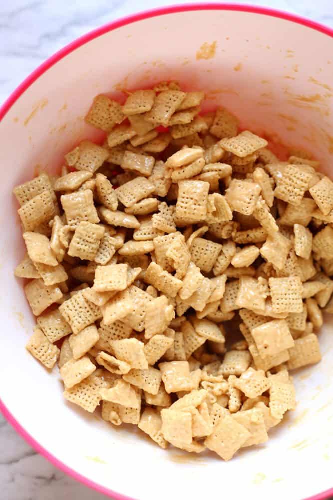 chex, peanut butter, white chocolate chips in a bowl stirred together.