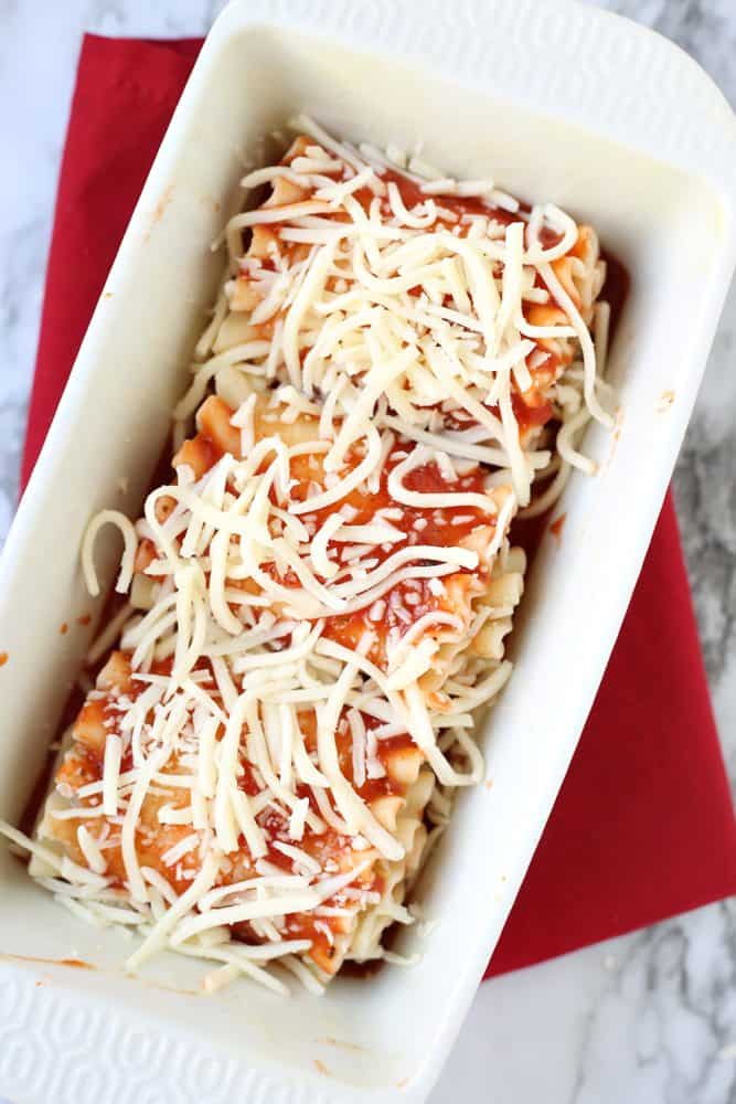 mozarella cheese sprinkled on lasagna roll ups in a baking dish.
