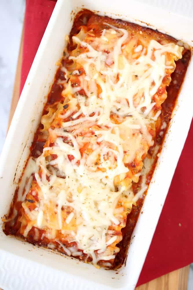 Easy Lasagna Roll Ups recipe with melted mozzarella cheese on top in a white baking dish.
