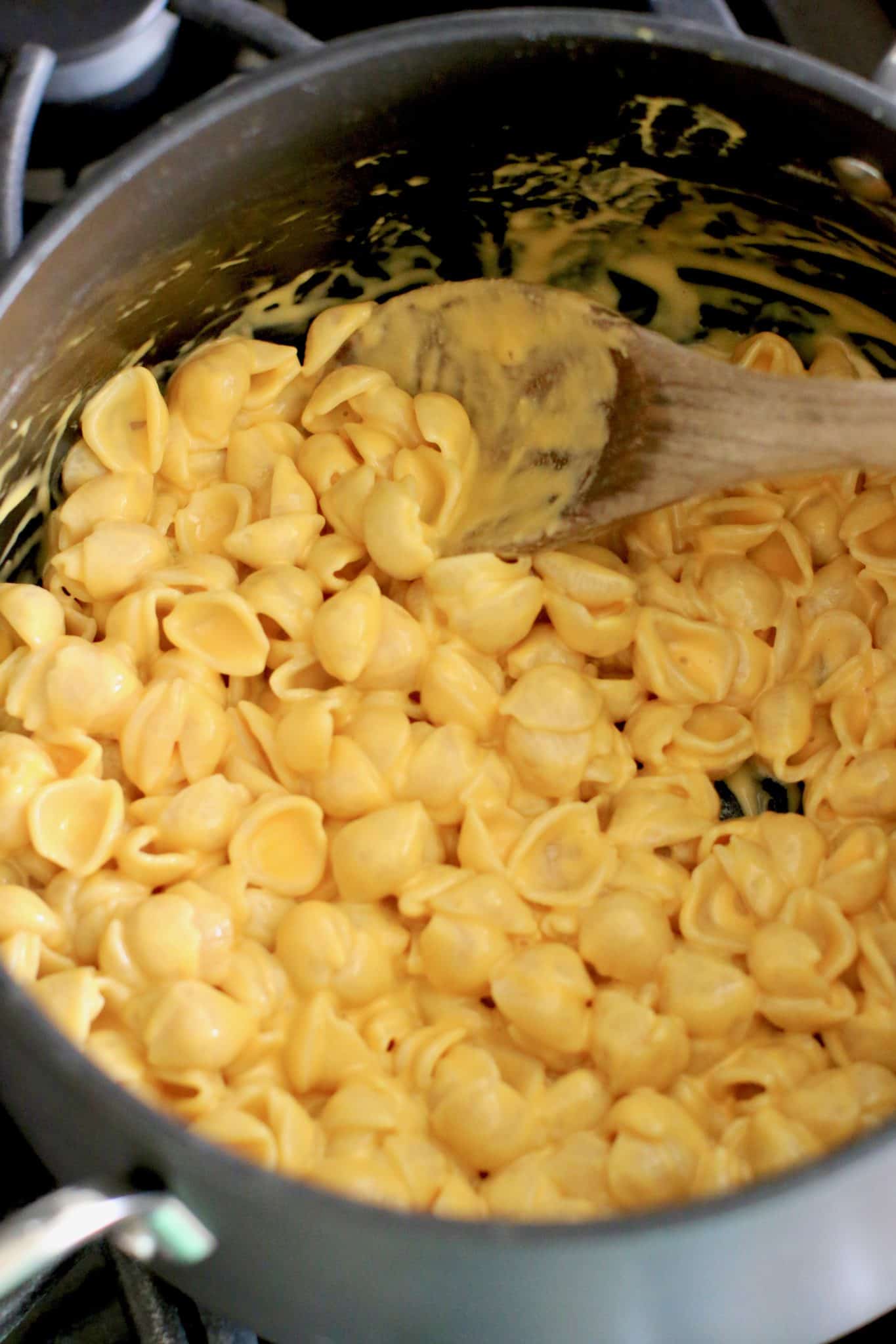prepared box shells and cheese in a pot with a wooden spoon.