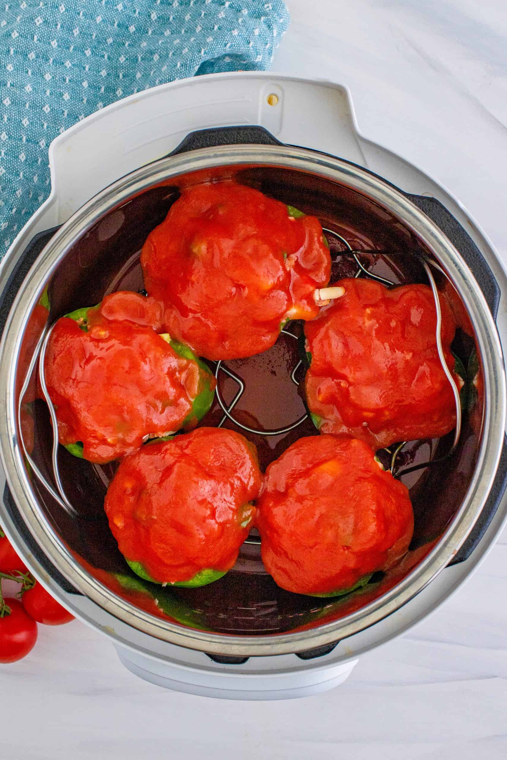 tomato sauce evenly spread on top of stuffed peppers.