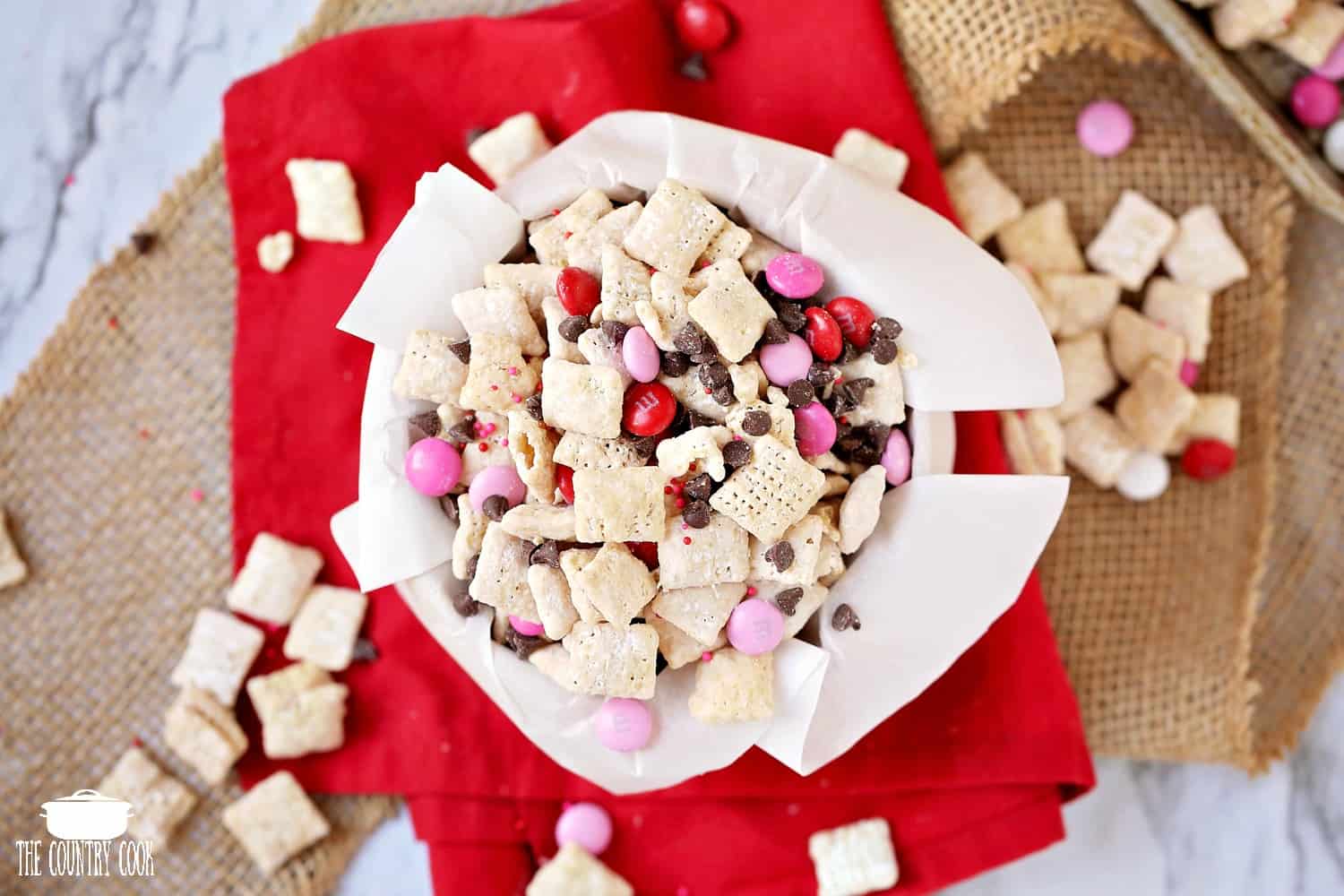 Valentine's Day Muddy Buddy Chex Mix in a bowl with parchment paper.