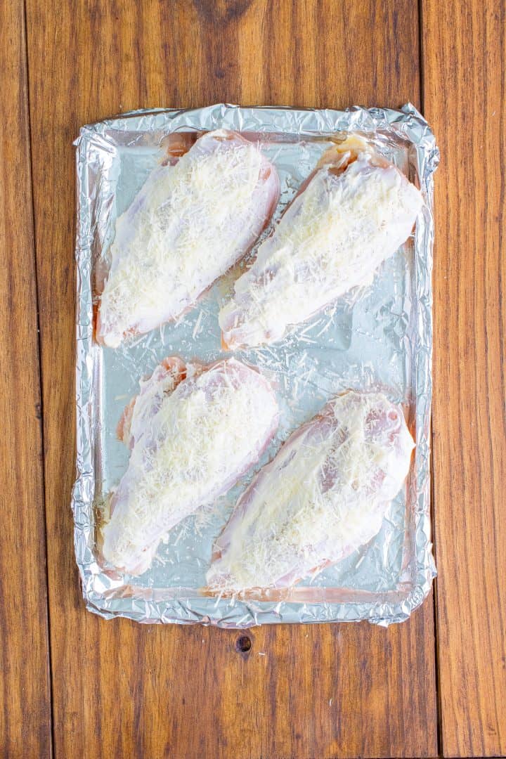 parmesan cheese sprinkled on top of mayonnaise coated chicken breasts.