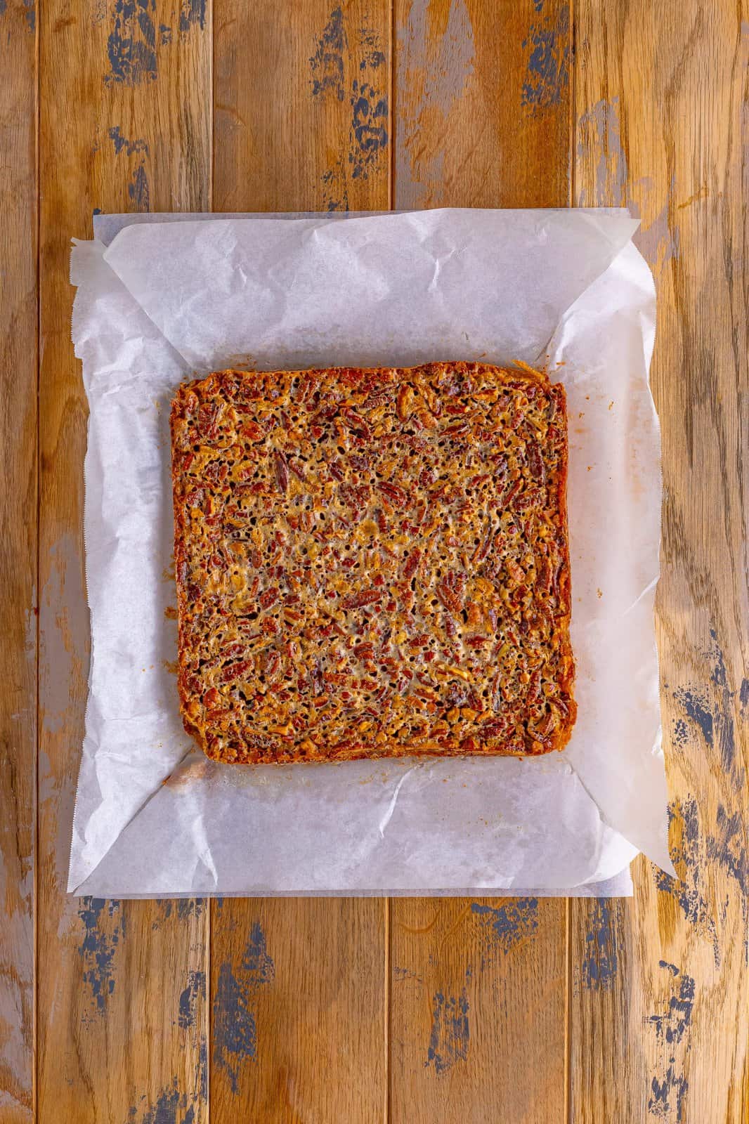 fully baked pecan pie bars shown on parchment paper. 