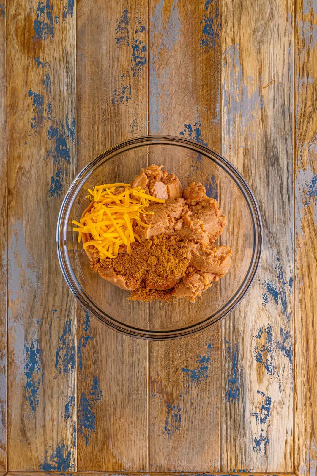 refried beans and shredded cheese mixed together in a bowl.