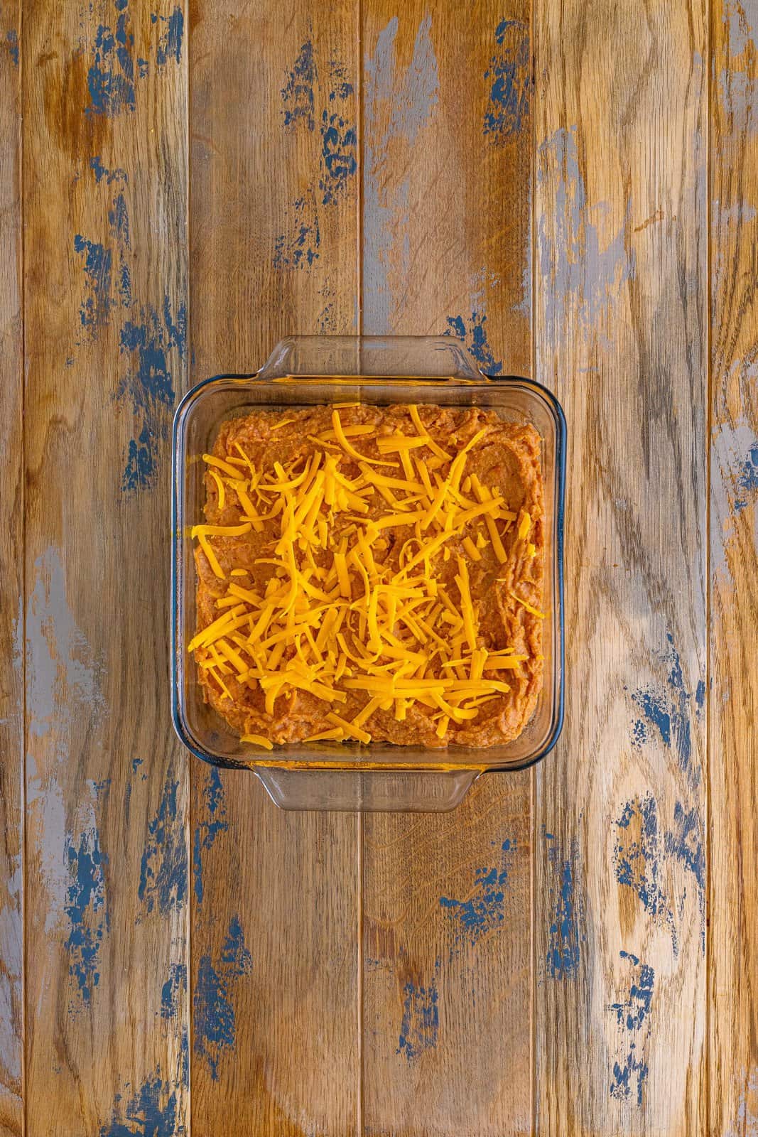 refried bean mixture spread into a baking dish and topped with shredded cheese. 