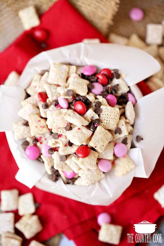 Muddy Buddy snack mix in a bowl that is lined with white parchment paper. 