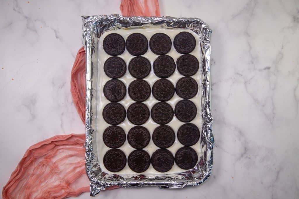 oreo cookies laid out in a single layer on top of melted white chocolate