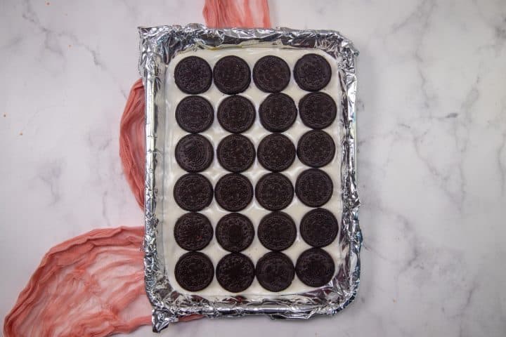 oreo cookies laid out in a single layer on top of melted white chocolate.