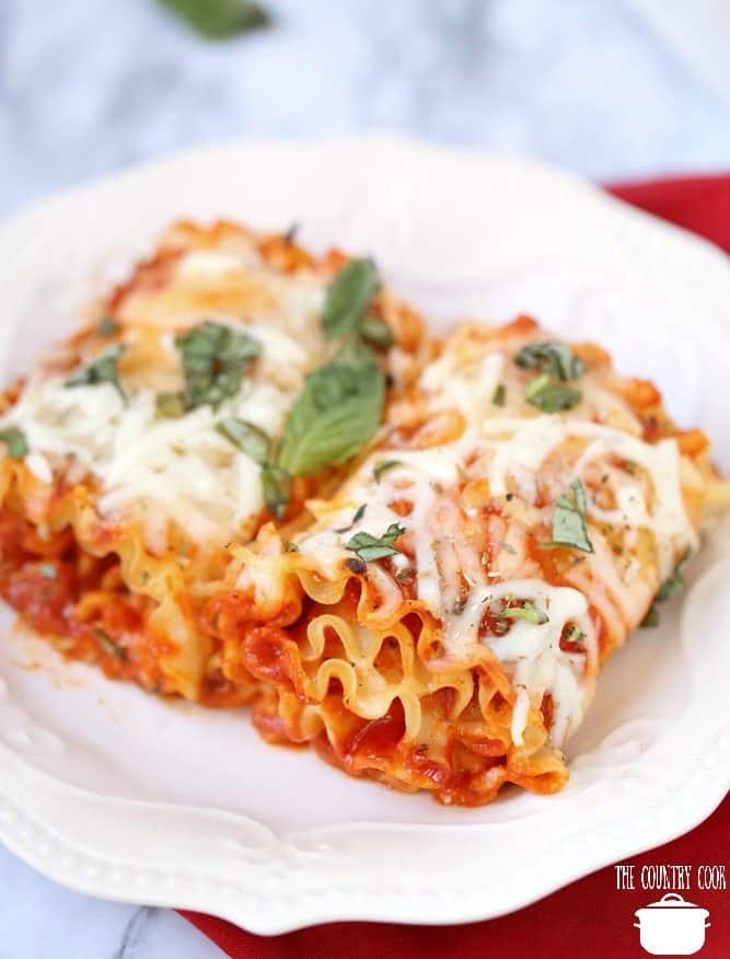 Easy Lasagna Rollups on a white plate topped with fresh basil.