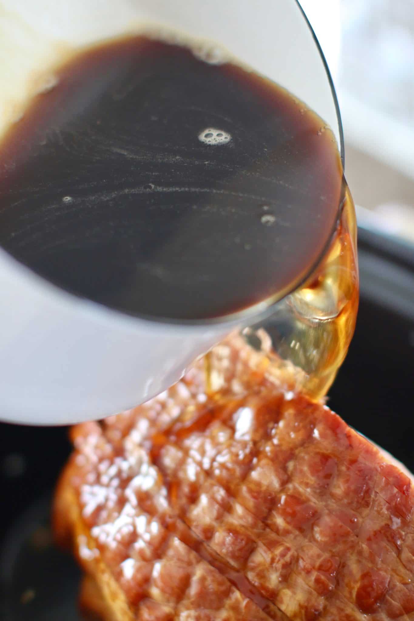 sweet tea and brown sugar glaze poured on top of spiral sliced ham in an oval slow cooker.