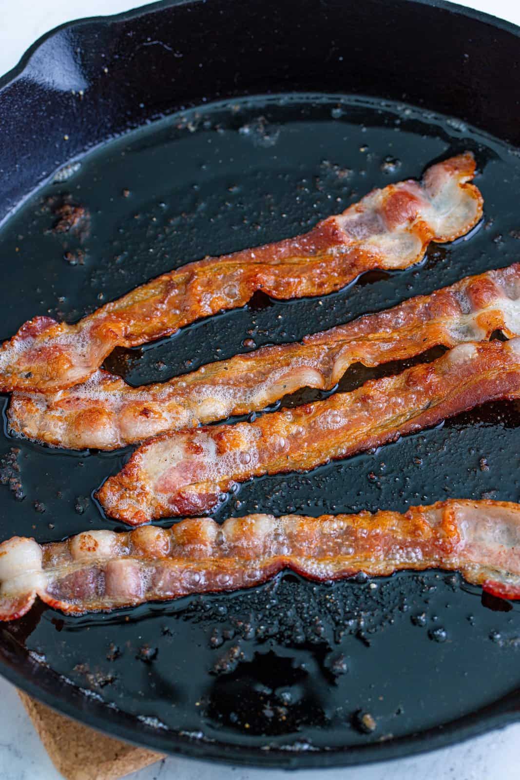 bacon cooking in a large skillet. 