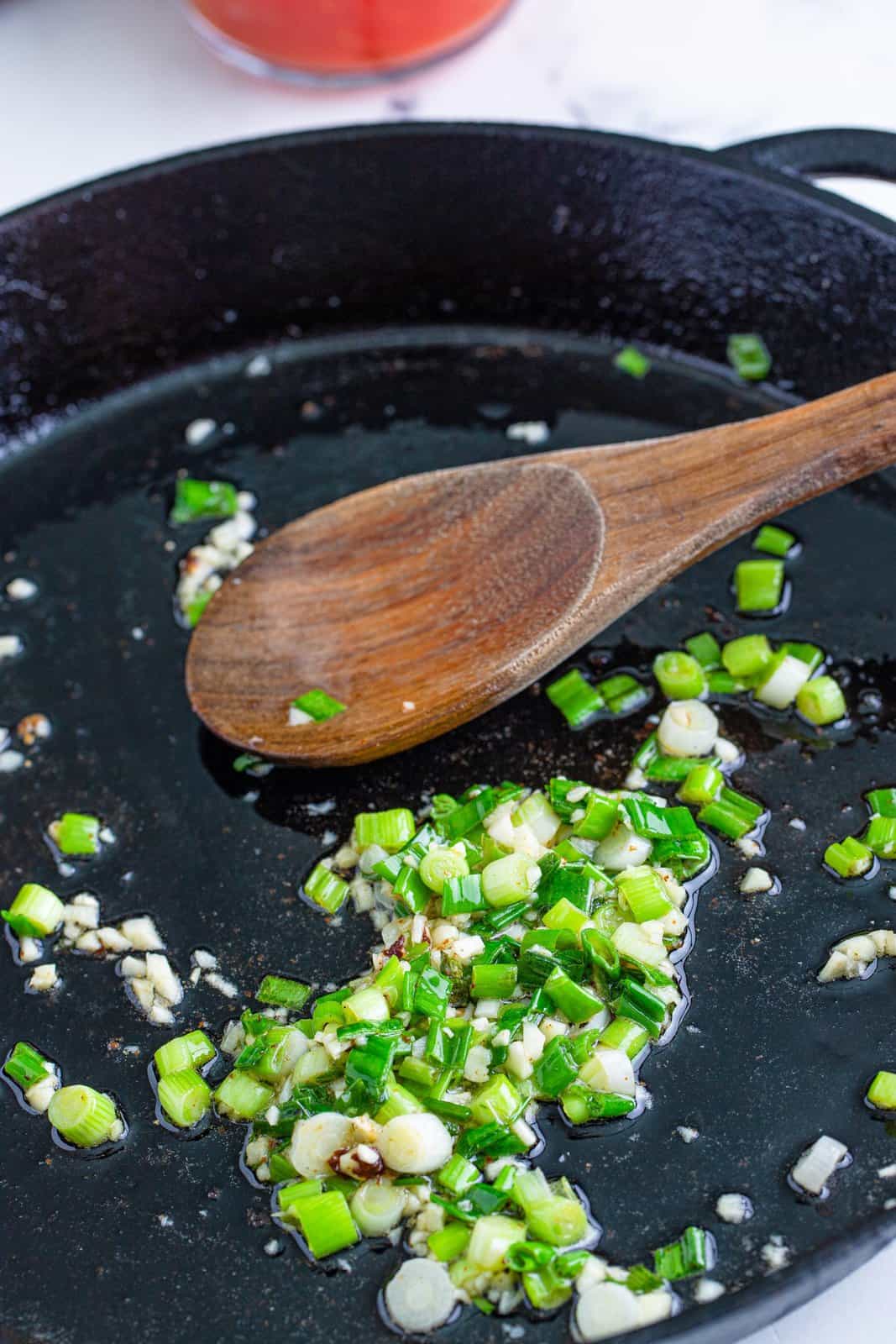 cooking sliced green onions in a skillet. 