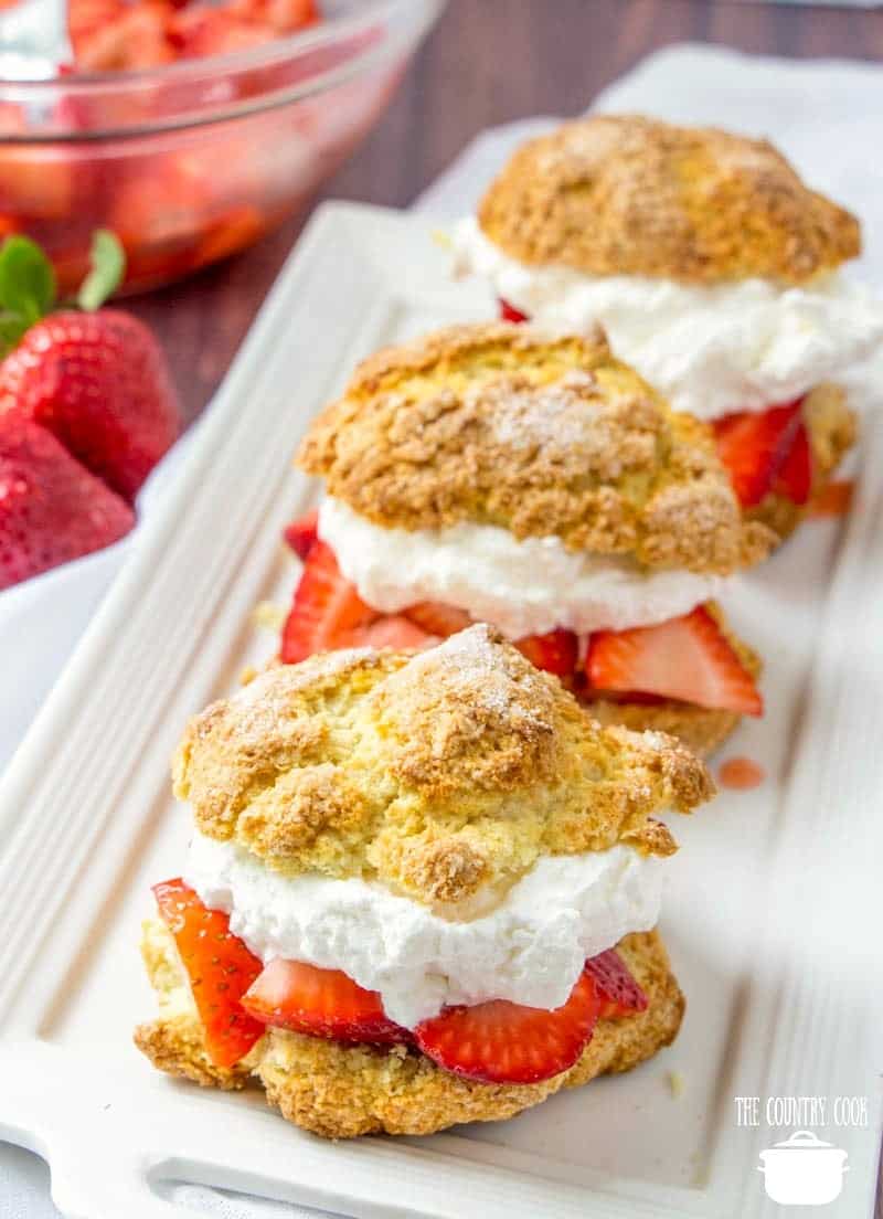 strawberry shortcakes with fresh strawberries and whipped cream on a white platter.