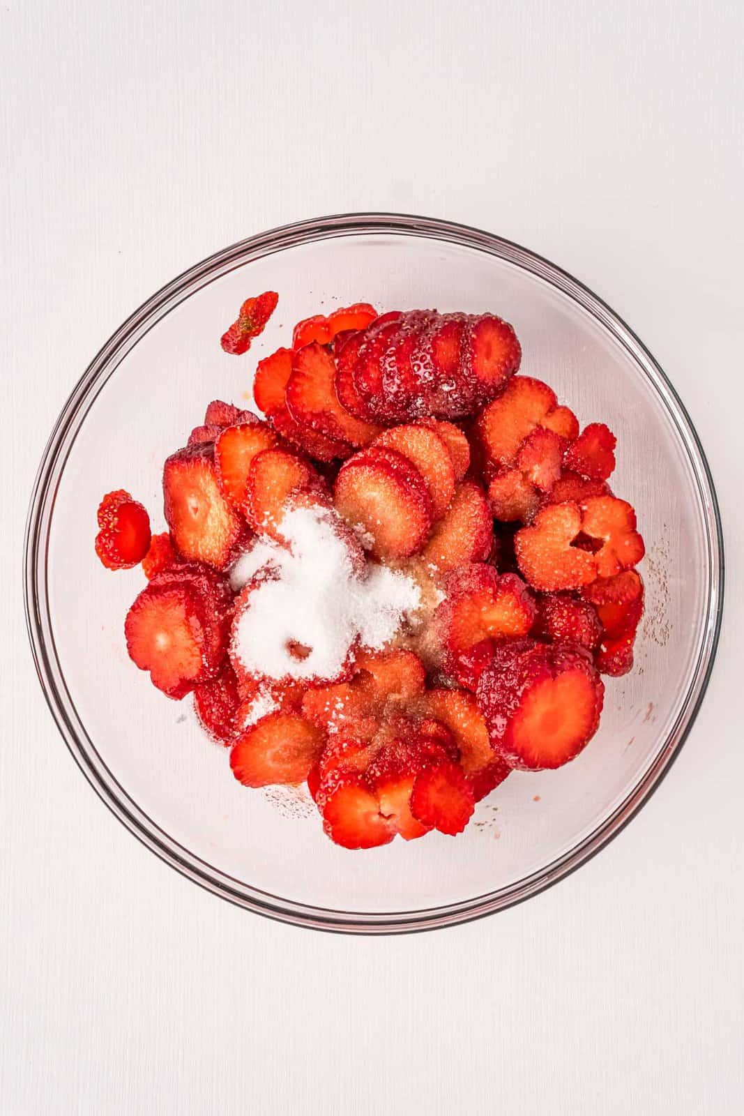 sliced strawberries, sugar and vanilla extract in a glass bowl.