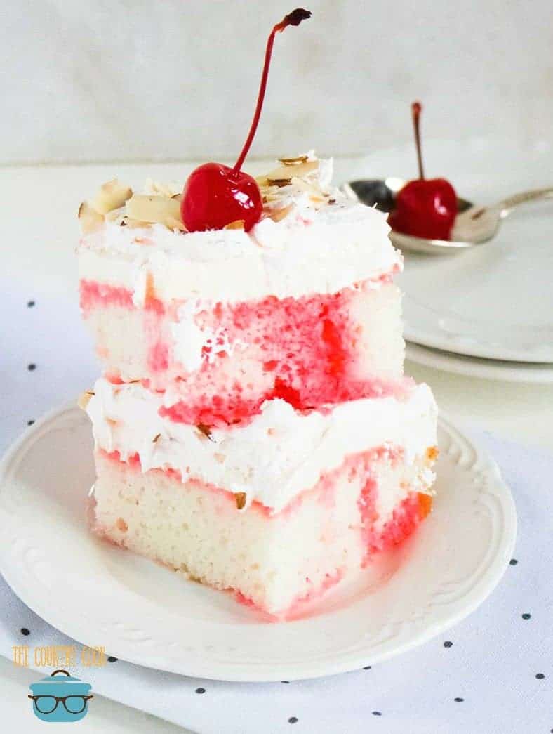 close up photo of two slices of cherry almond poke cake stacked on top of each other. 