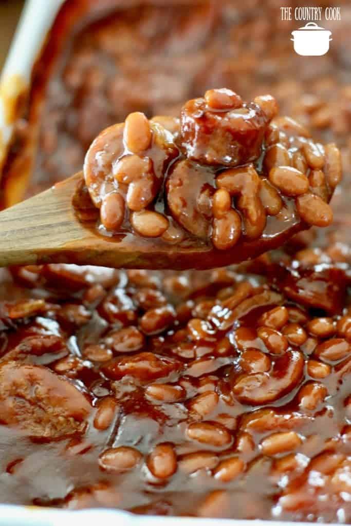 Easy Sausage Baked Beans scooped with wooden spoon