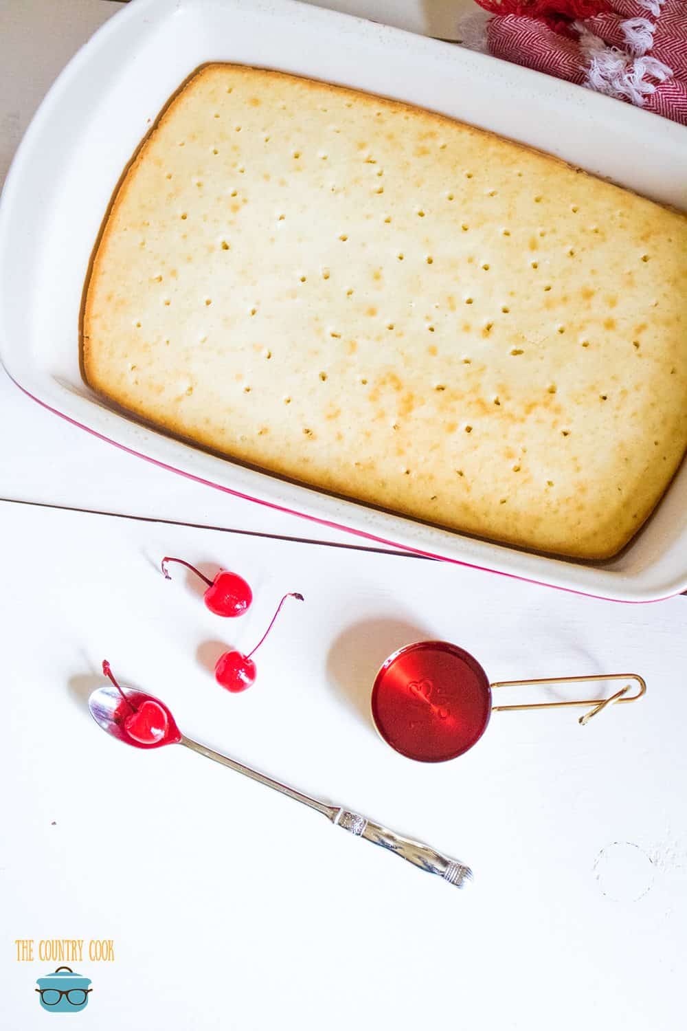 cooled white cake in a 9x13-inch baking dish with poked holes.