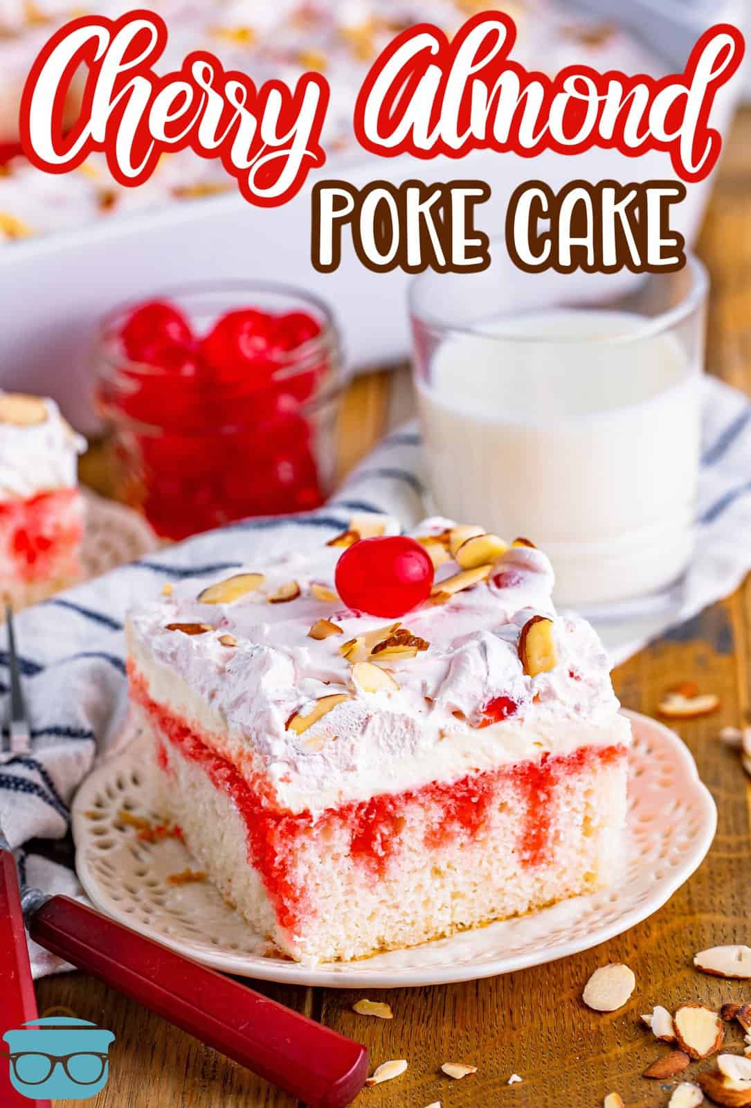 slice of Cherry Almond Poke Cake on a plate with a glass of milk shown in the background.
