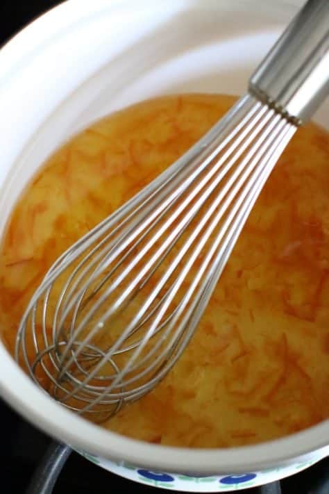 Orange marmalade with apple cider vinegar whisked together in a pot.