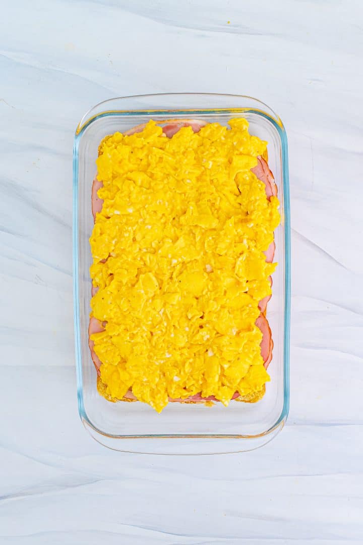 scrambled eggs layered on top of ham layer in baking dish.