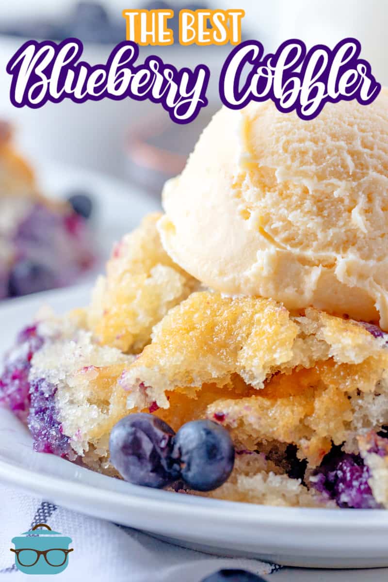 Easy Blueberry Cobbler recipe from The Country Cook, close up photo of a  serving of blueberry cobbler on a white plate and topped with a scoop of vanilla ice cream.