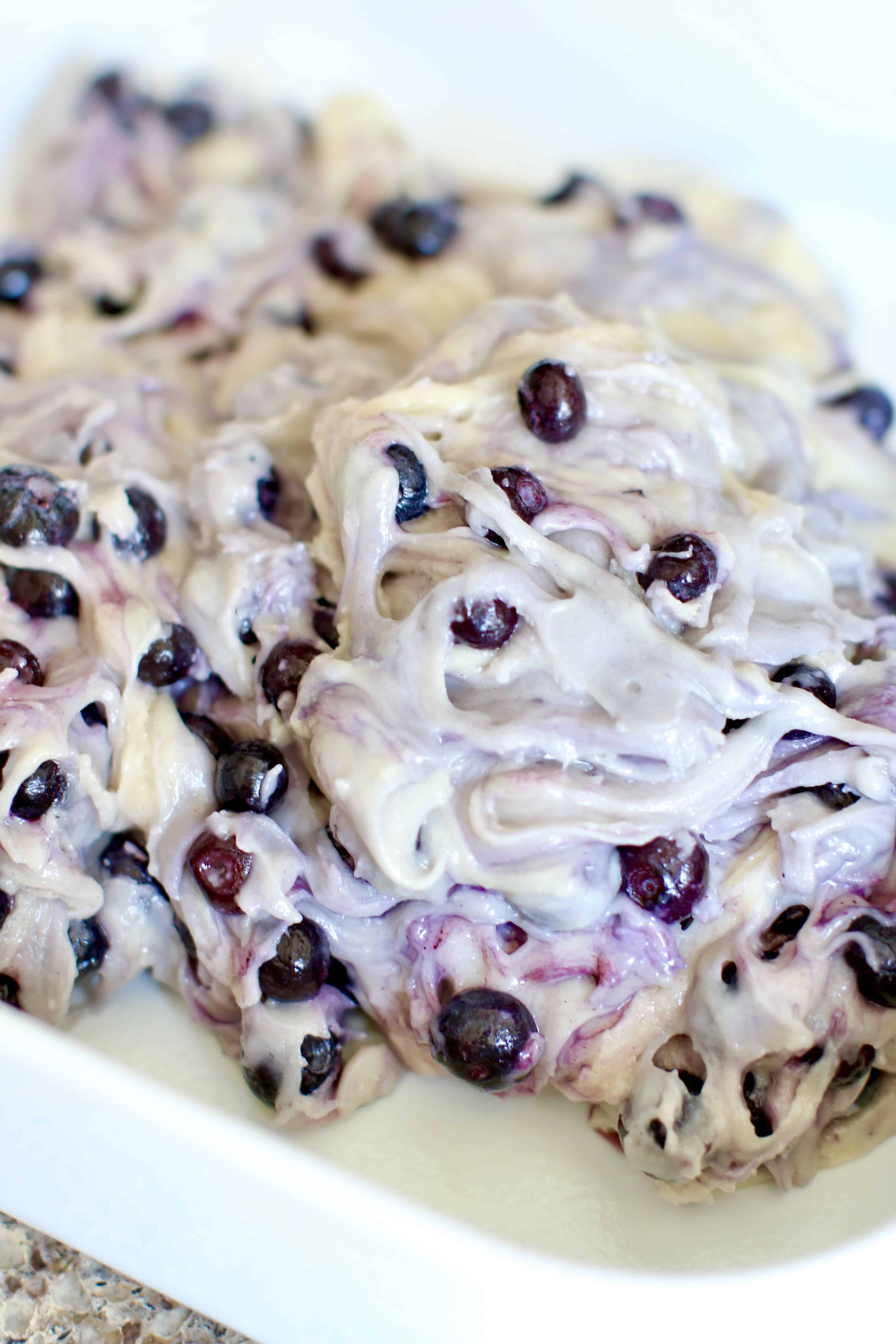 blueberry buckle cake batter spread into a white 9-inch square baking dish.