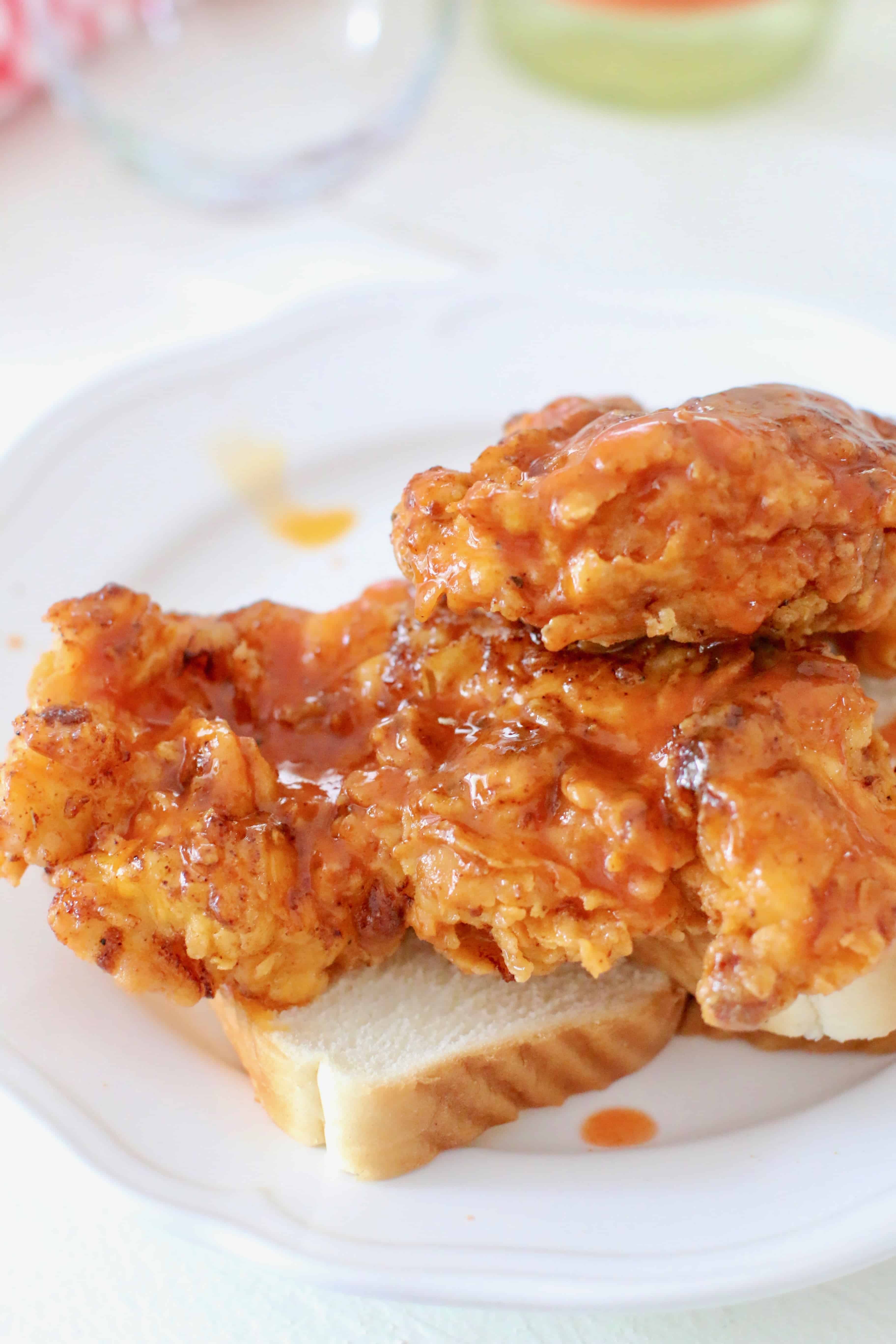 Nashville Hot Chicken sauce poured on top of fried chicken breasts on white bread.
