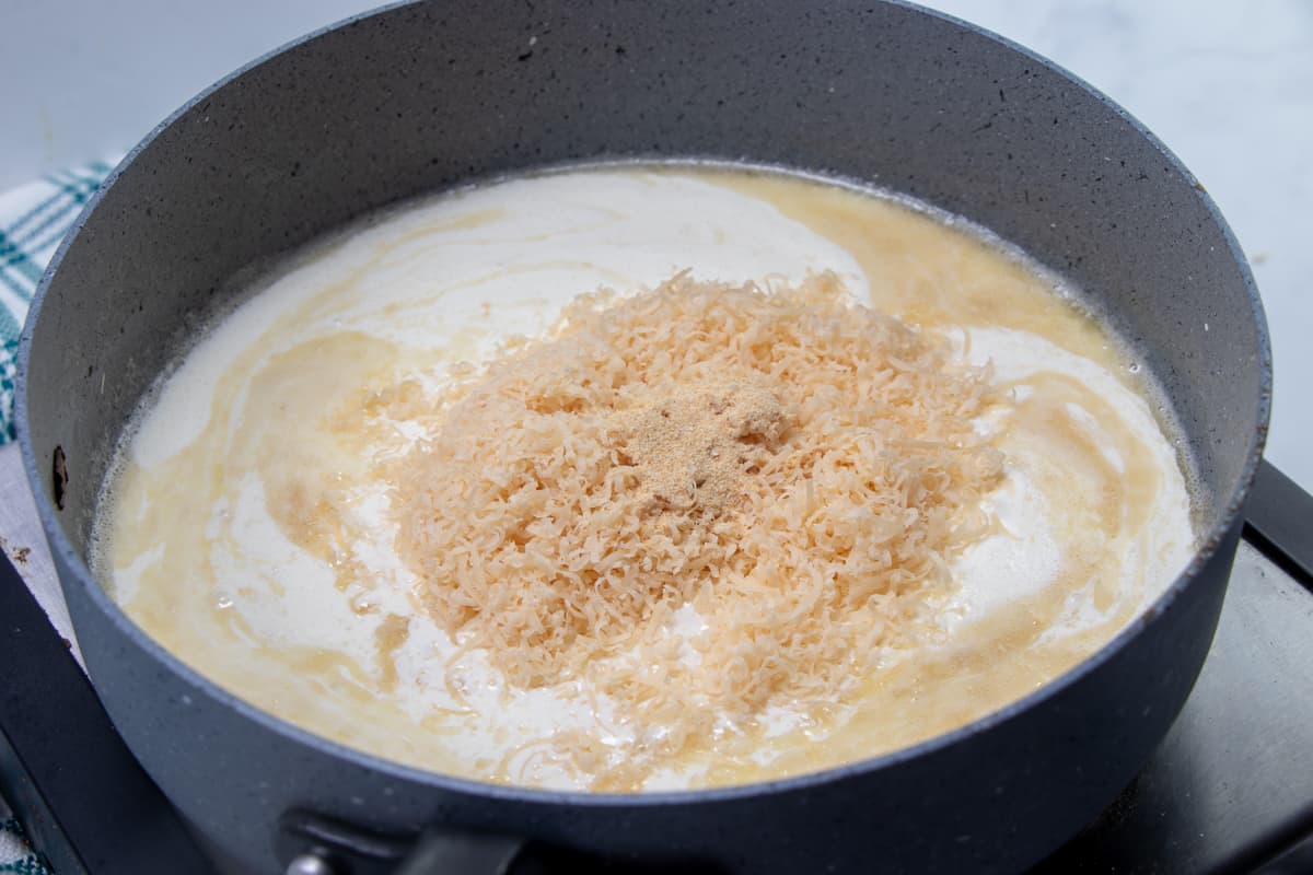 freshly grated Parmesan cheese added to heavy cream and roux mixture in a large skillet.