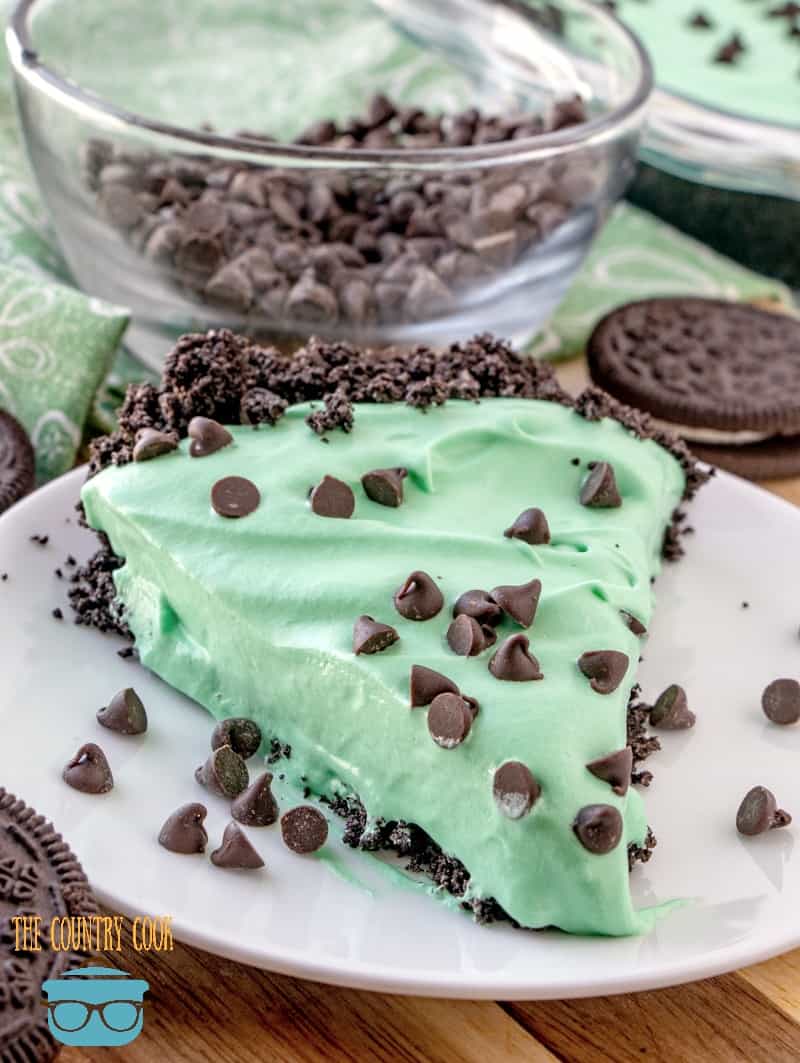 a slice of grasshopper pie shown on a white plate with Oreo cookies in the background.