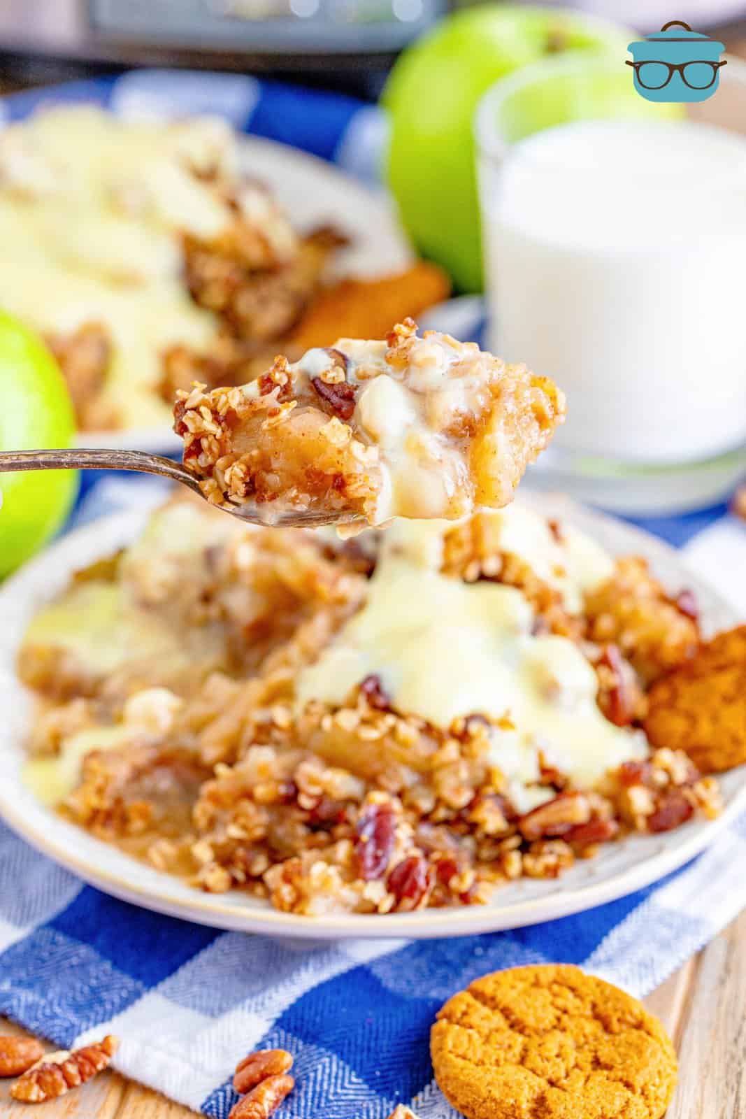 a fork scooping up some apple crisp off a plate.