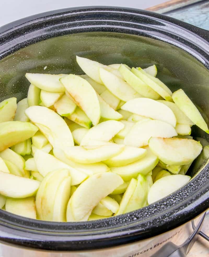 sliced green apples placed in the bottom of a 6 quart oval slow cooker.