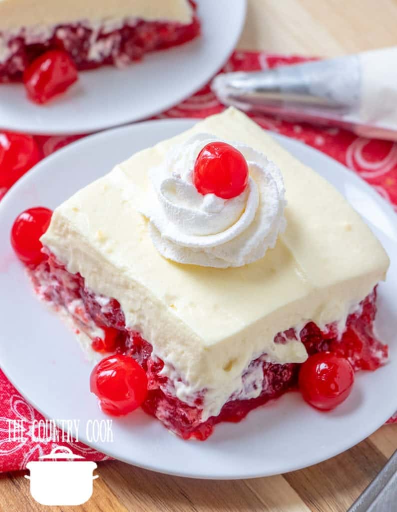 Cherry Jell-O Dessert, slice on a white plate with maraschino cherries