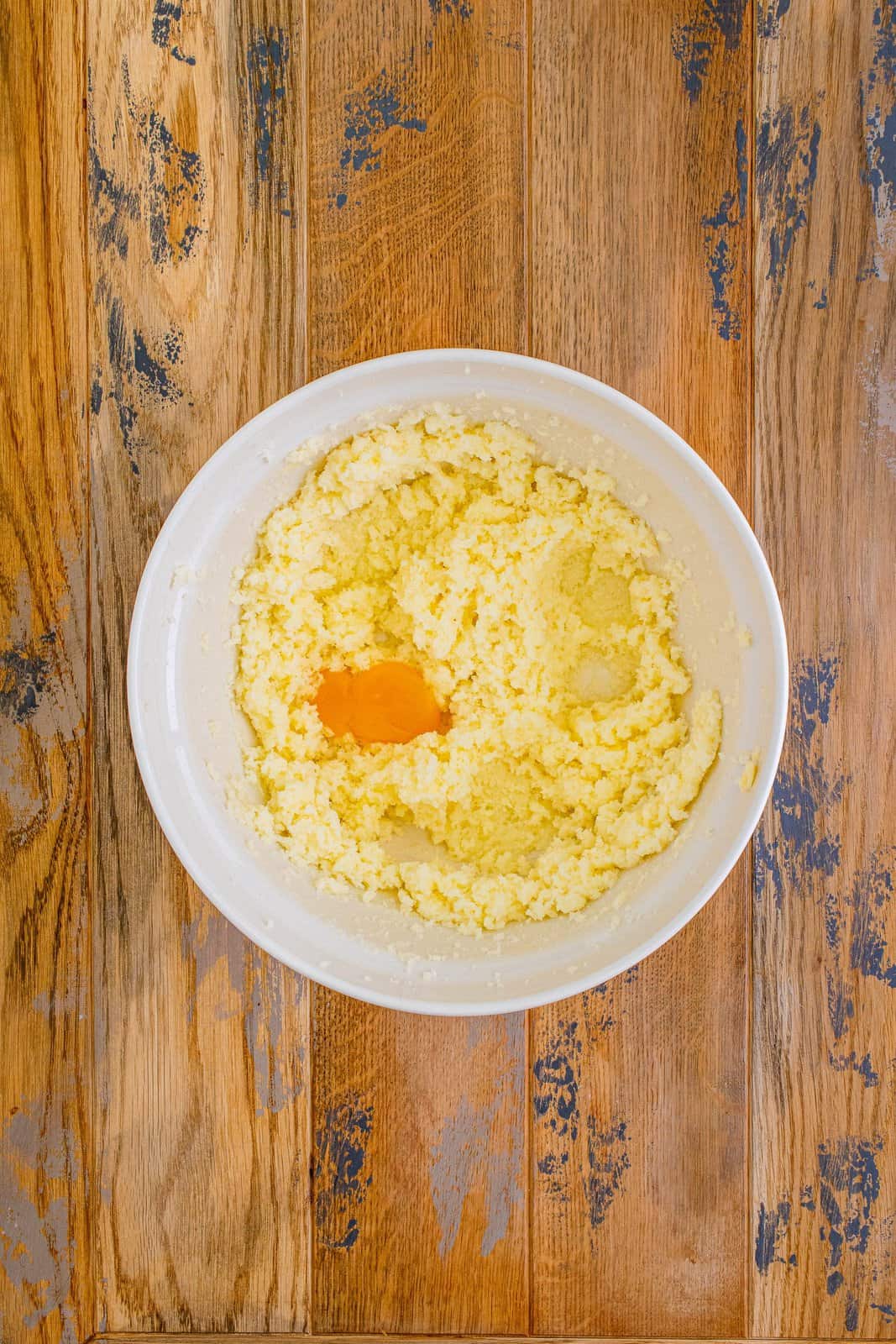 adding eggs to butter sugar mixture in a bowl.