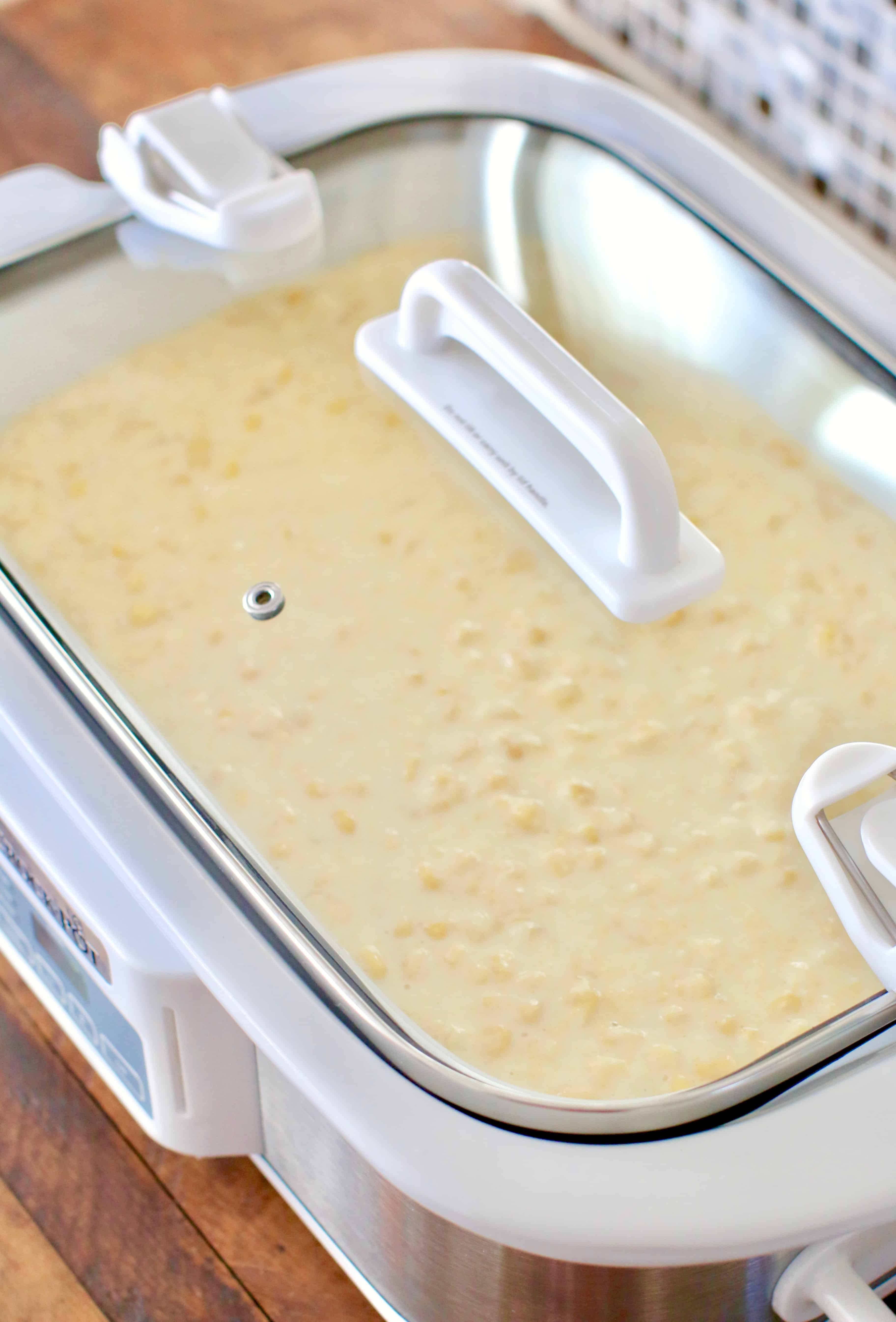 casserole crock pot pictured with corn casserole batter inside and a clear lid on top.