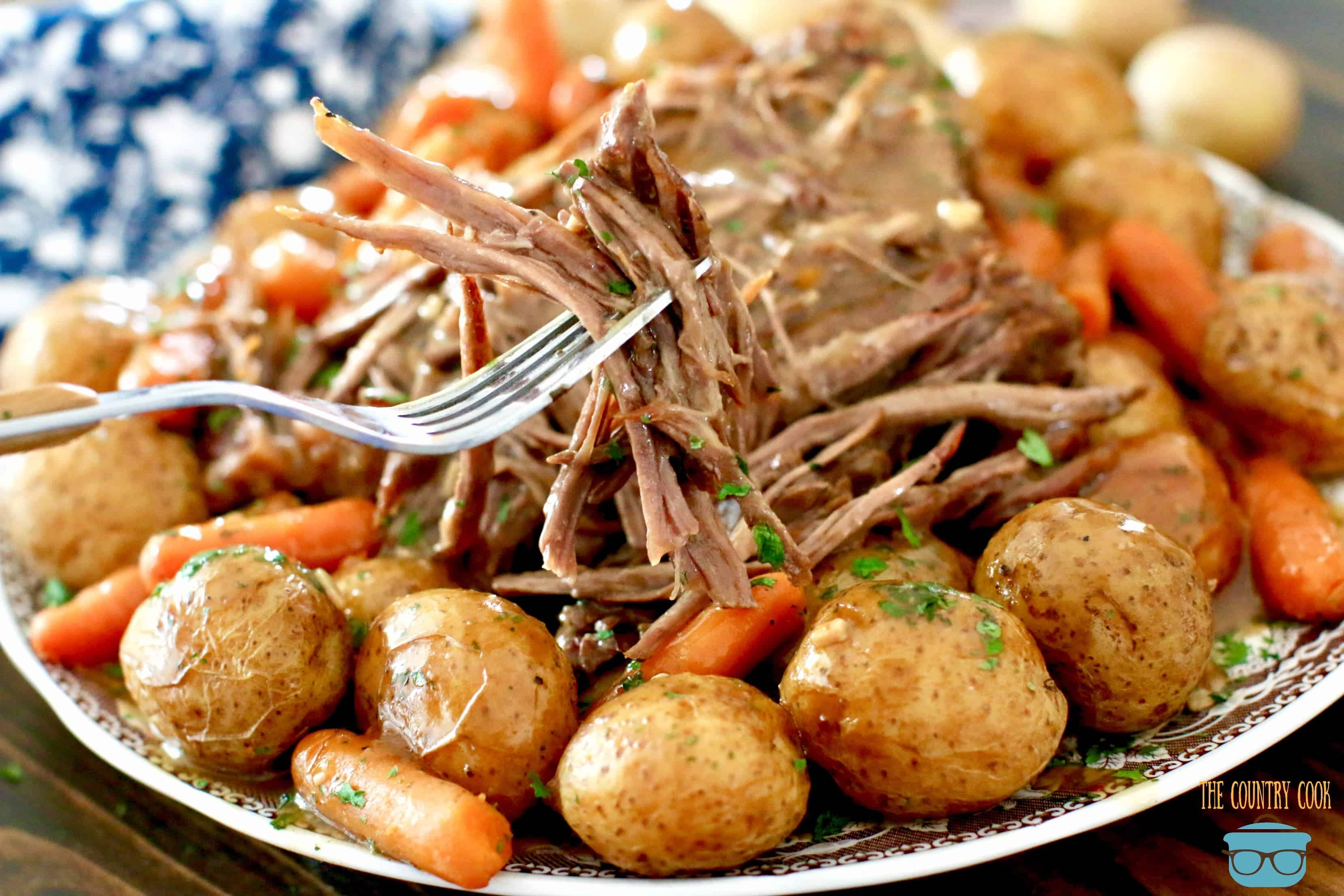 Electric Pressure Cooker Beef Pot Roast with potatoes and carrots and gravy shown on a plate.