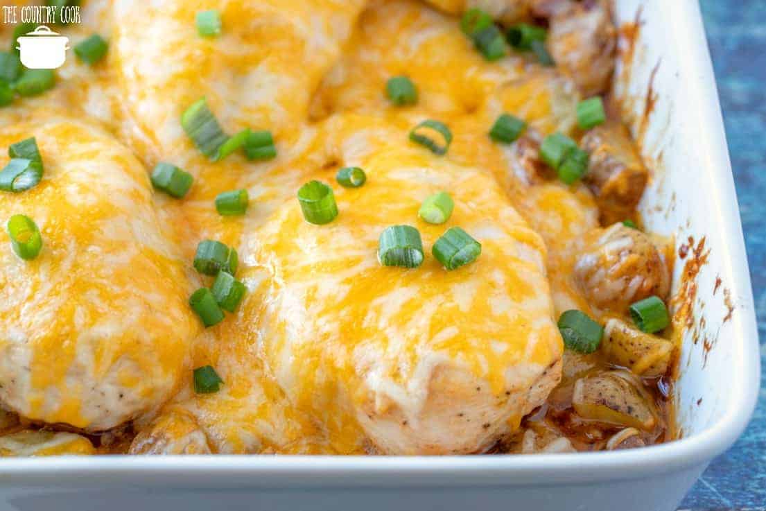horizontal photo of fully baked chicken and potato casserole in a white baking dish with melted cheese on top of the chicken breasts.
