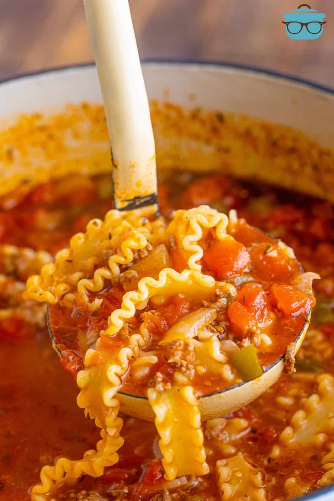 a ladle holding up lasagna soup over the pot. 