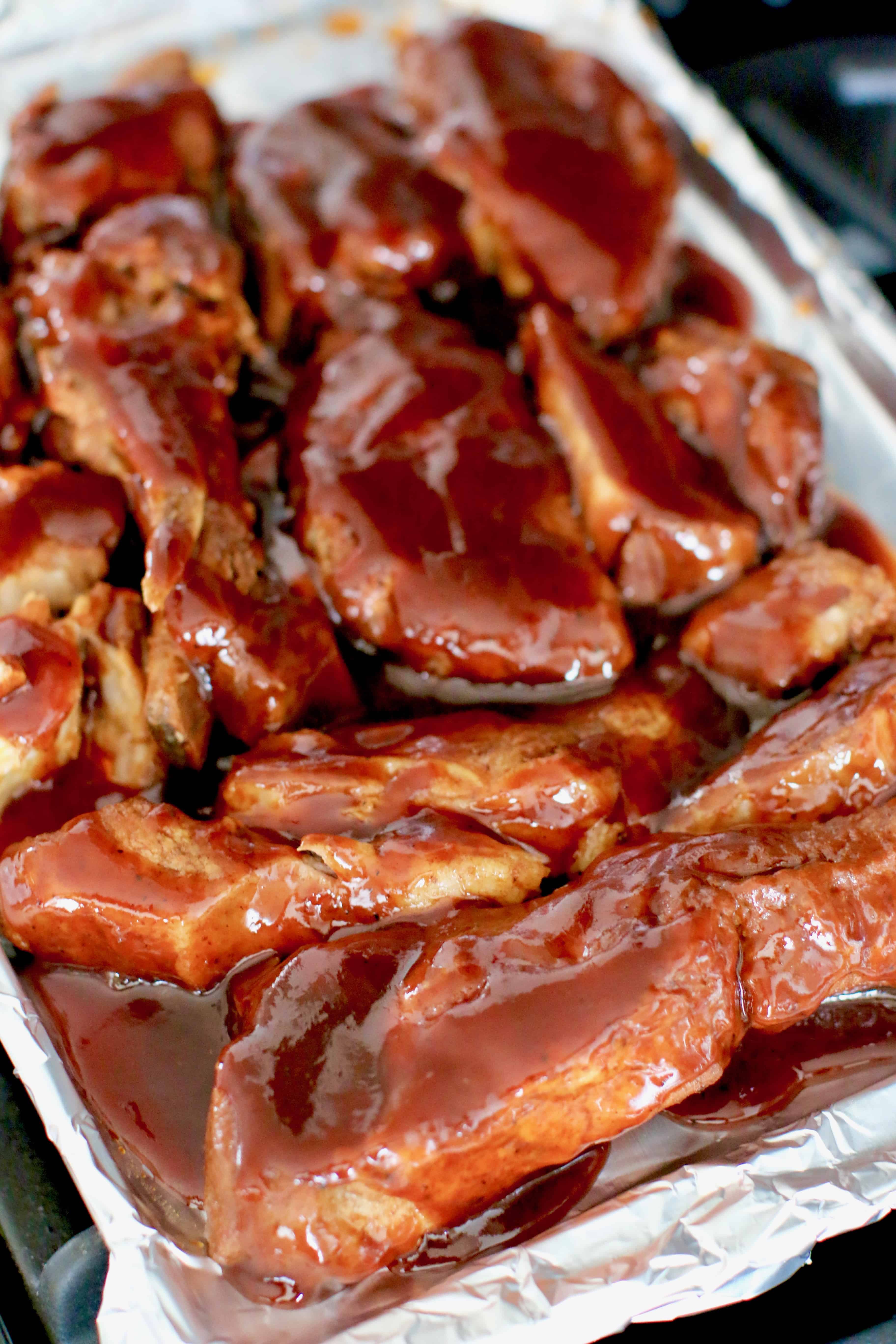 Korean BBQ sauce poured over cooked country style ribs on a baking sheet.