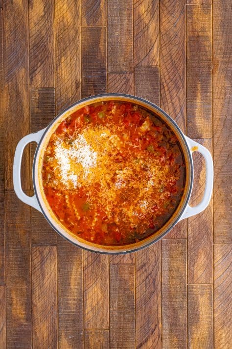 Parmesan cheese added to lasagna soup in pot.