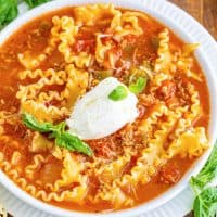 a white bowl filled with lasagna soup topped with ricotta cheese.
