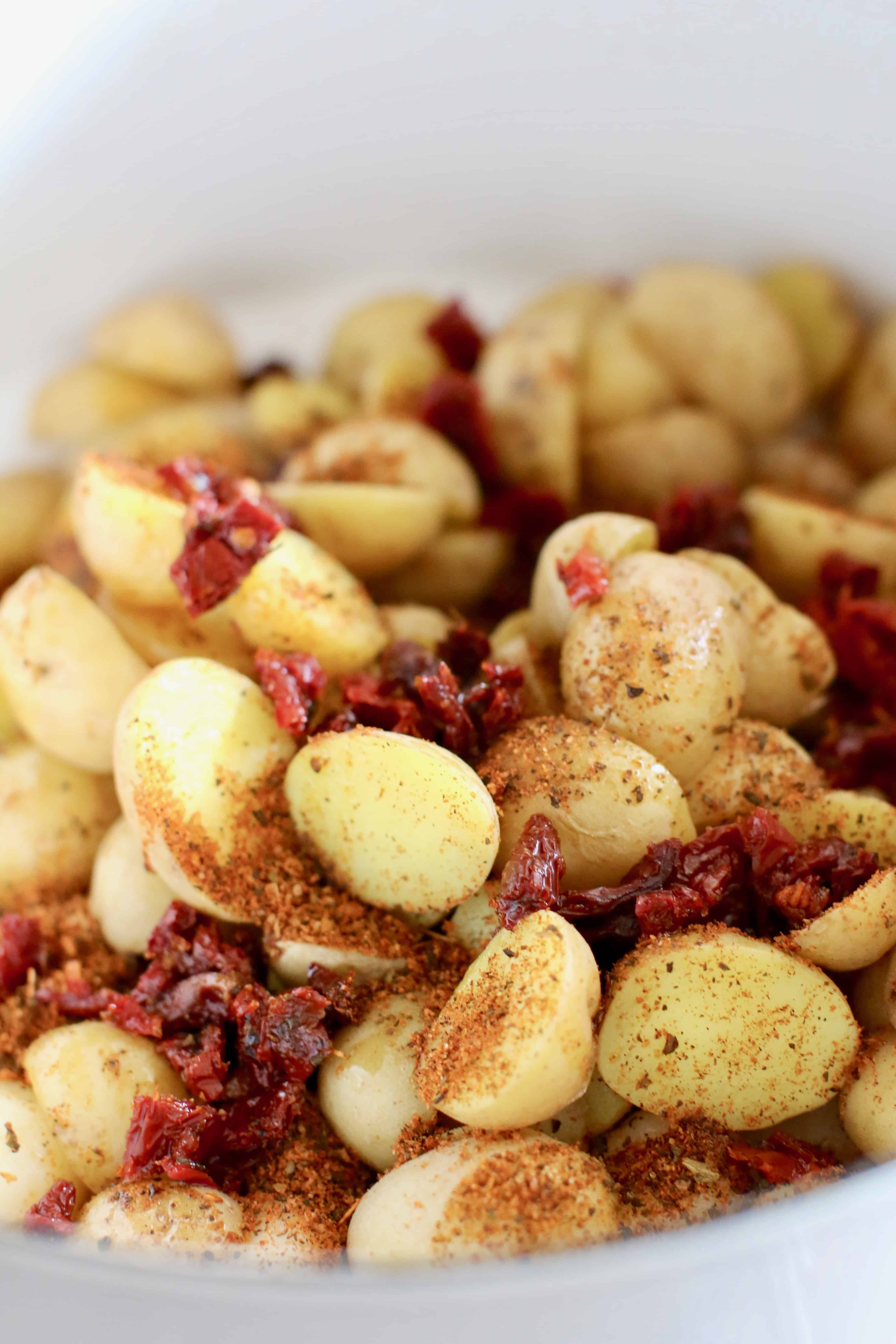sprinkle packet of Tomato Basil seasoning on potatoes and gnocchi in a white pot.