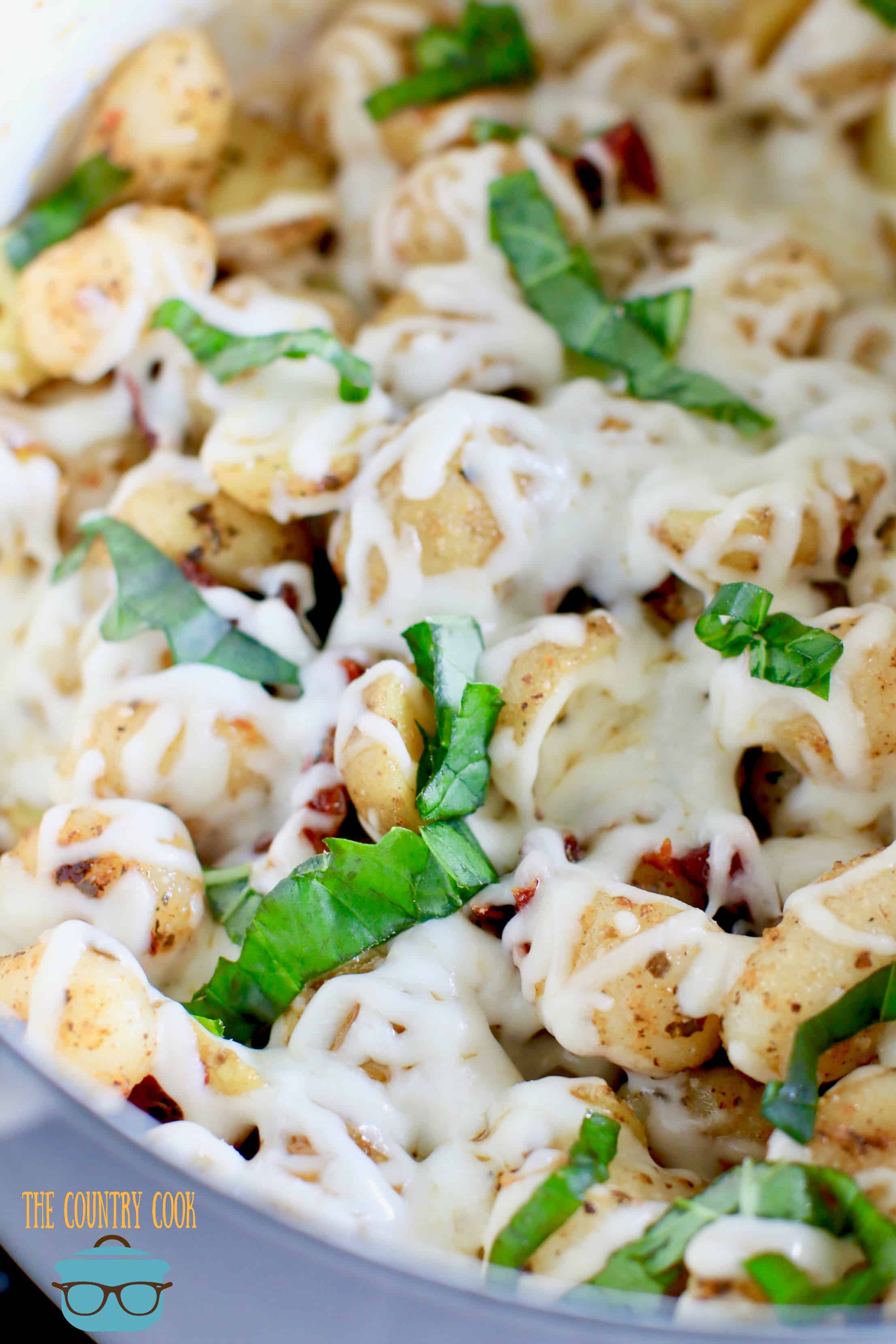 Easy Cheesy Italian Potatoes and Gnocchi shown fully cooked and topped with fresh shredded basil.