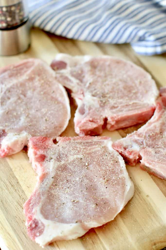 seasoned bone-in pork chops on a cutting board.