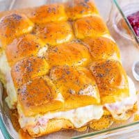 Glazed ham and cheese sliders in a clear baking dish.